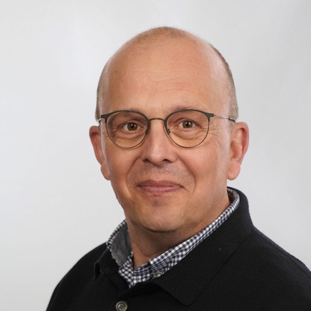 Mann trägt Brille und Hemd, professionelles Portrait für Medien und Kommunikation.